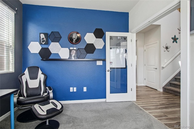 sitting room featuring an accent wall, baseboards, plenty of natural light, and stairway