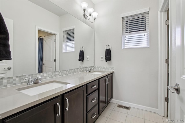bathroom featuring baseboards, a sink, and a healthy amount of sunlight