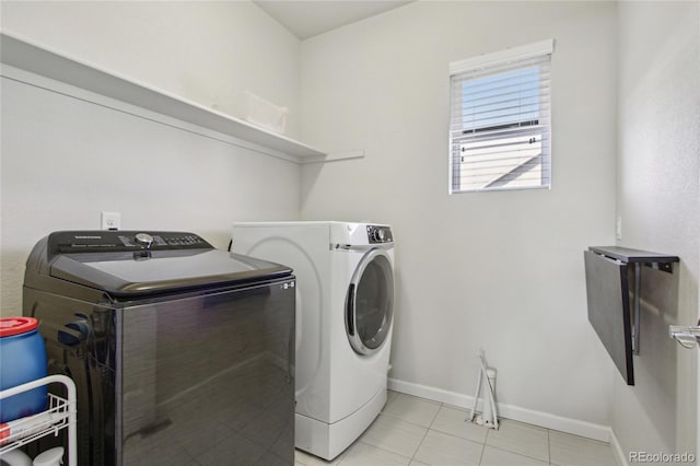 clothes washing area with light tile patterned floors, baseboards, laundry area, and washing machine and dryer