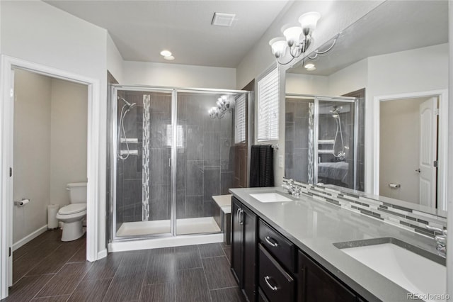 full bath with a sink, a shower stall, toilet, and a chandelier