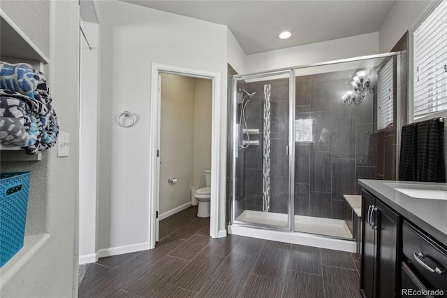 bathroom with vanity, toilet, baseboards, and a stall shower