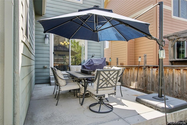 view of patio featuring grilling area, fence, and outdoor dining area