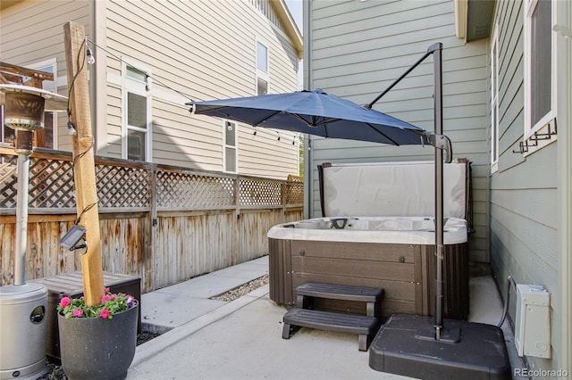 view of patio with a hot tub and fence