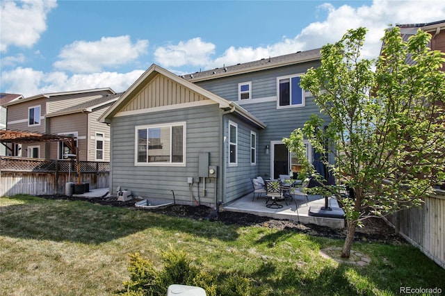 rear view of property featuring a fenced backyard, board and batten siding, a lawn, and a patio area