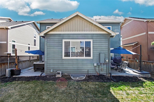 rear view of house featuring a lawn, fence, board and batten siding, and a patio area