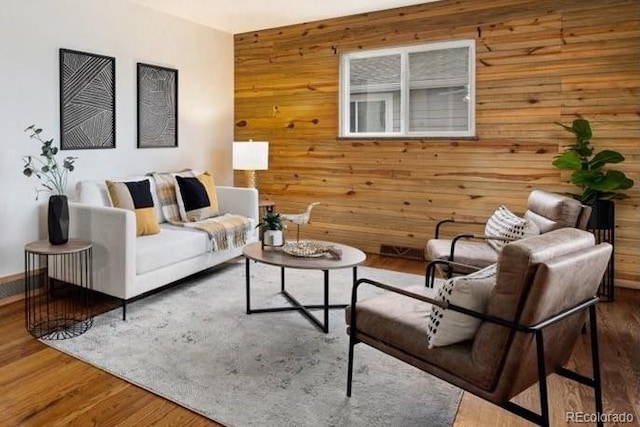 living area with wooden walls and wood finished floors