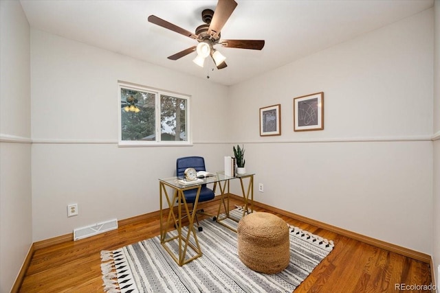 office area featuring a ceiling fan, wood finished floors, visible vents, and baseboards