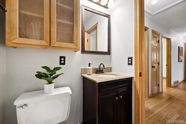 bathroom with vanity, toilet, wood finished floors, and visible vents