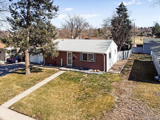 ranch-style home featuring brick siding, an attached garage, fence, a front yard, and driveway