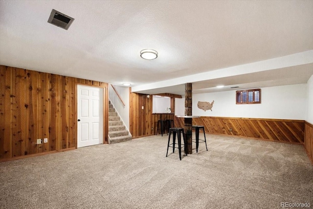 interior space with visible vents, wood walls, stairway, and light colored carpet