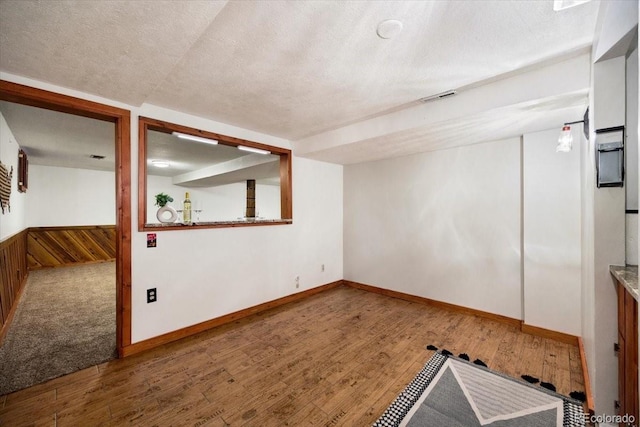 interior space with visible vents, wainscoting, a textured ceiling, and hardwood / wood-style floors