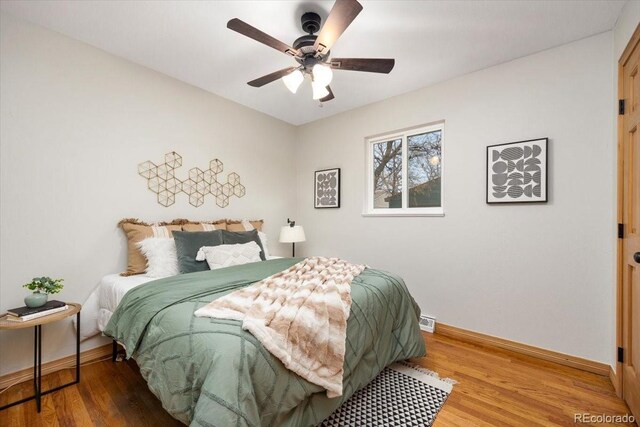 bedroom featuring baseboards, wood finished floors, and a ceiling fan