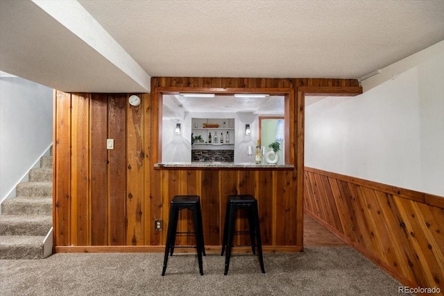 bar with stairway, wood walls, a bar, and carpet