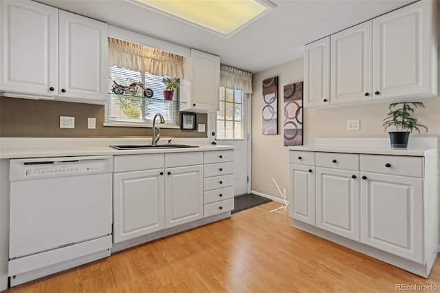 kitchen featuring dishwasher, light countertops, a sink, and white cabinets