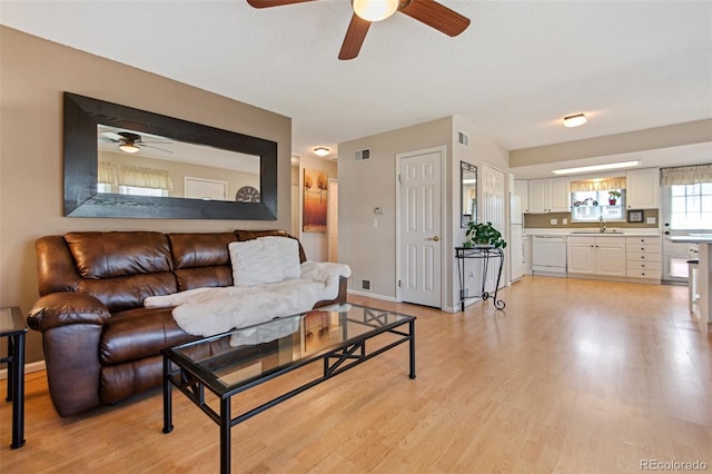 living area featuring light wood-style floors, visible vents, and baseboards