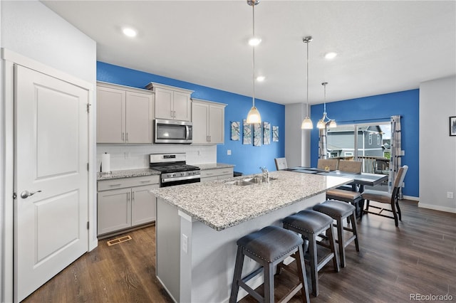2144 Rosette Ln, Castle Rock, CO 80104 - kitchen featuring stainless steel appliances, a sink, decorative backsplash, dark wood-style flooring, and a breakfast bar