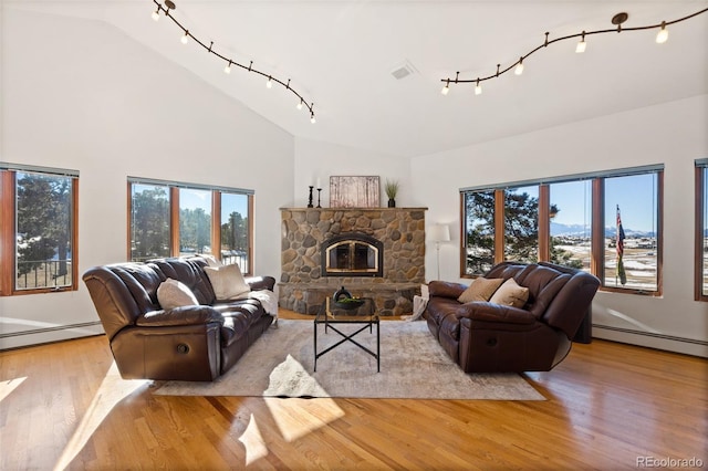 living room featuring a fireplace, light hardwood / wood-style floors, a baseboard radiator, and a wealth of natural light