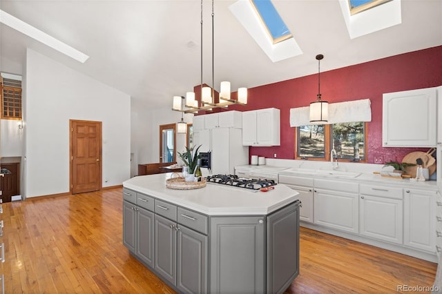 kitchen featuring gray cabinetry, decorative light fixtures, a kitchen island, white cabinetry, and gas cooktop