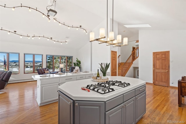 kitchen featuring gray cabinetry, a center island, white gas cooktop, a baseboard heating unit, and decorative light fixtures