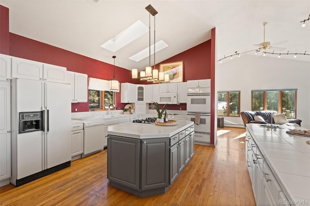 kitchen featuring white cabinets, plenty of natural light, white appliances, and a skylight