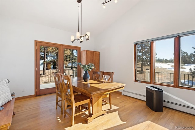 dining area with a chandelier, light hardwood / wood-style floors, high vaulted ceiling, and a baseboard heating unit