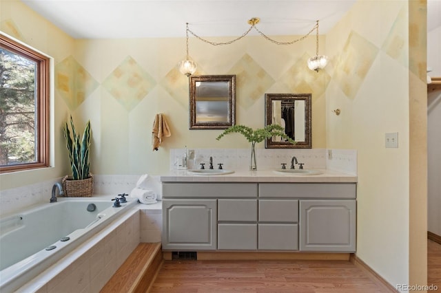 bathroom with tiled bath, hardwood / wood-style floors, and vanity