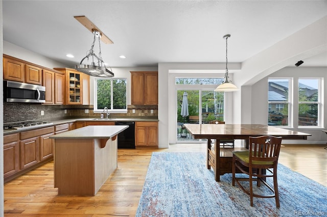 kitchen featuring appliances with stainless steel finishes, a kitchen island, brown cabinets, and tasteful backsplash