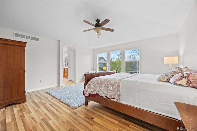 bedroom with a ceiling fan, baseboards, visible vents, arched walkways, and light wood-style floors
