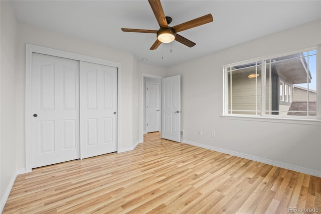 unfurnished bedroom featuring baseboards, a closet, a ceiling fan, and light wood-style floors