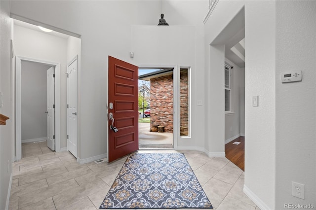 foyer featuring a towering ceiling, baseboards, and light tile patterned flooring
