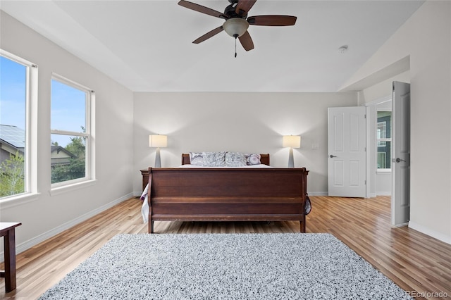 bedroom featuring baseboards, light wood-type flooring, and a ceiling fan