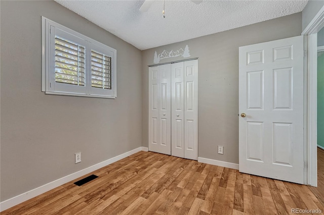 unfurnished bedroom featuring light wood finished floors, a closet, baseboards, a textured ceiling, and ceiling fan