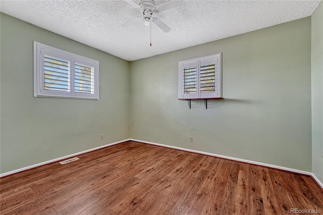 empty room with wood finished floors, ceiling fan, baseboards, and a textured ceiling