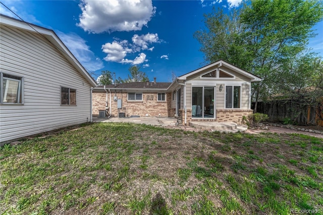rear view of house featuring brick siding, a patio, and fence