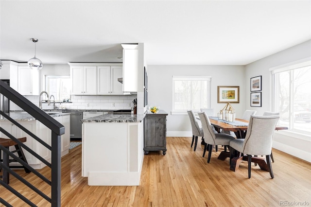 kitchen with baseboards, decorative backsplash, light wood-style flooring, a peninsula, and white cabinetry