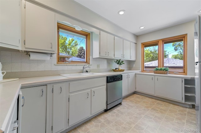 kitchen featuring dishwasher, a sink, light countertops, backsplash, and recessed lighting