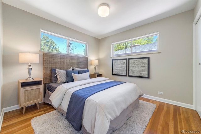 bedroom with multiple windows, baseboards, and light wood-style floors