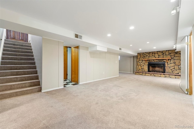 unfurnished living room with carpet floors, a stone fireplace, stairs, recessed lighting, and baseboards