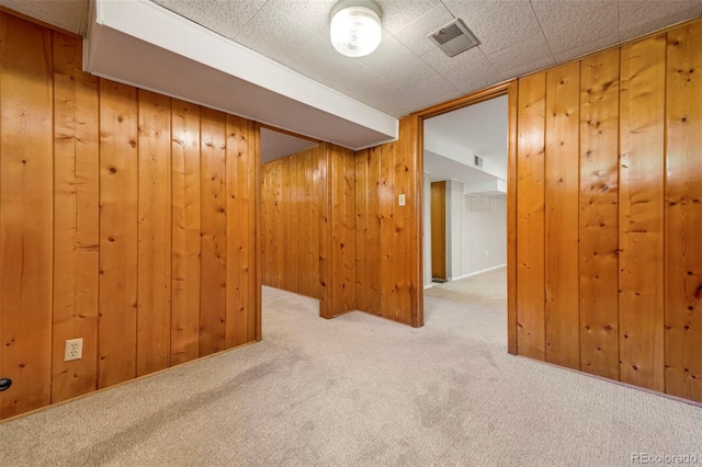 carpeted empty room featuring wood walls