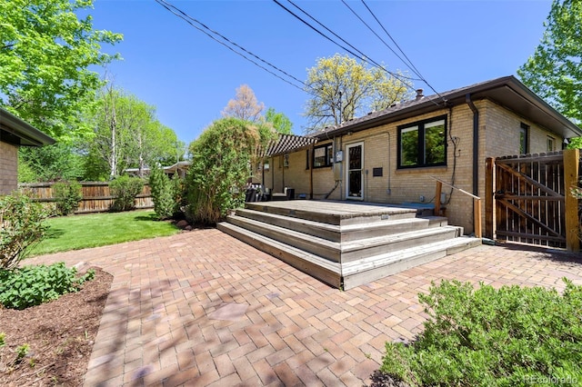 rear view of property featuring a patio, brick siding, a gate, and a deck