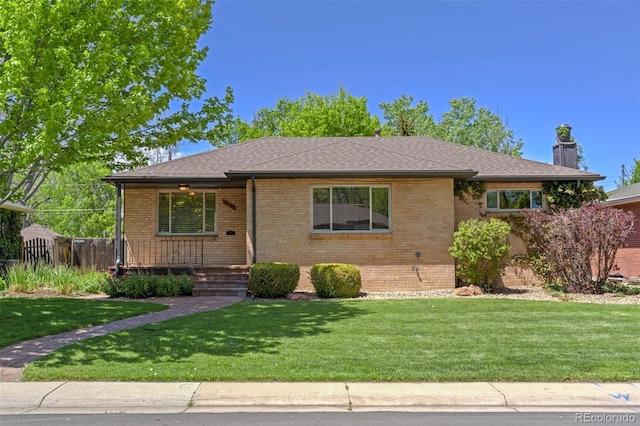 view of front of property with brick siding, a chimney, a front yard, and a porch
