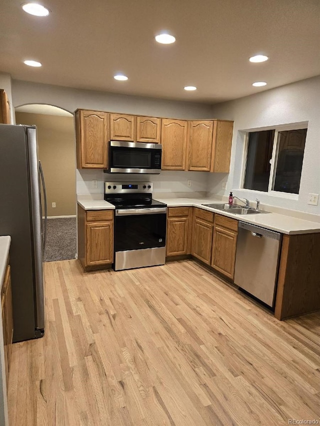 12742 Clermont St, Thornton, CO 80241 - kitchen featuring stainless steel appliances, light wood-type flooring, arched walkways, recessed lighting, and a sink
