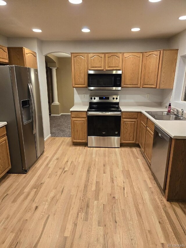 12742 Clermont St, Thornton, CO 80241 - kitchen featuring stainless steel appliances, a sink, arched walkways, ornate columns, and light wood-style flooring