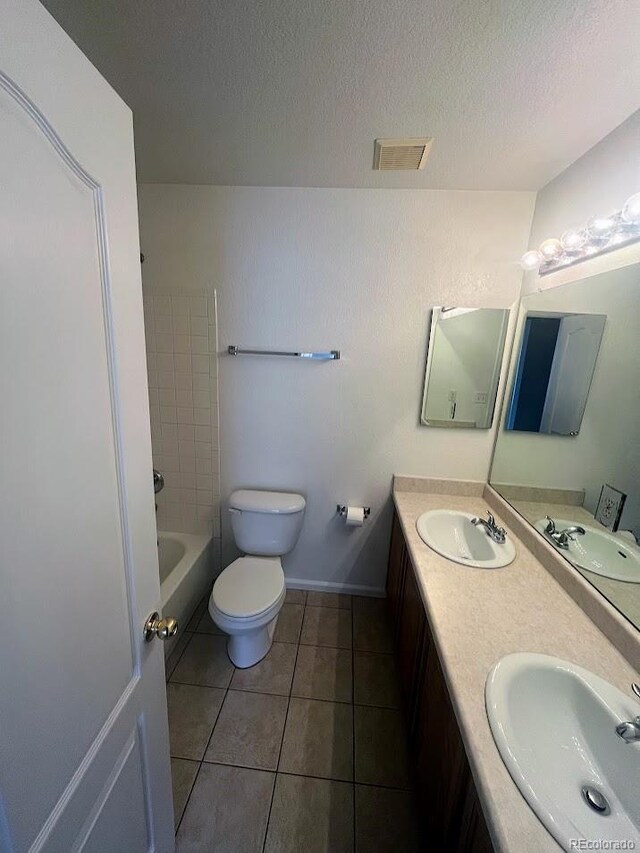 12742 Clermont St, Thornton, CO 80241 - full bath with double vanity, toilet, tile patterned floors, a textured ceiling, and shower / bathtub combination