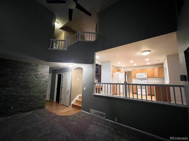 12742 Clermont St, Thornton, CO 80241 - unfurnished living room featuring ceiling fan, arched walkways, a towering ceiling, carpet floors, and stairs