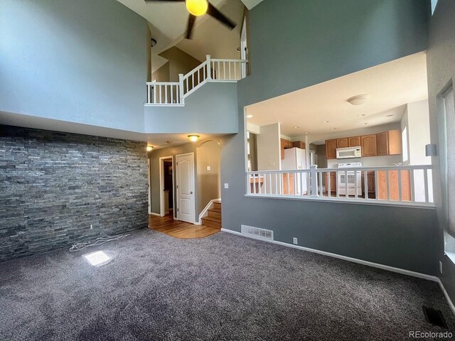 12742 Clermont St, Thornton, CO 80241 - unfurnished living room featuring carpet floors, ceiling fan, high vaulted ceiling, stairway, and baseboards