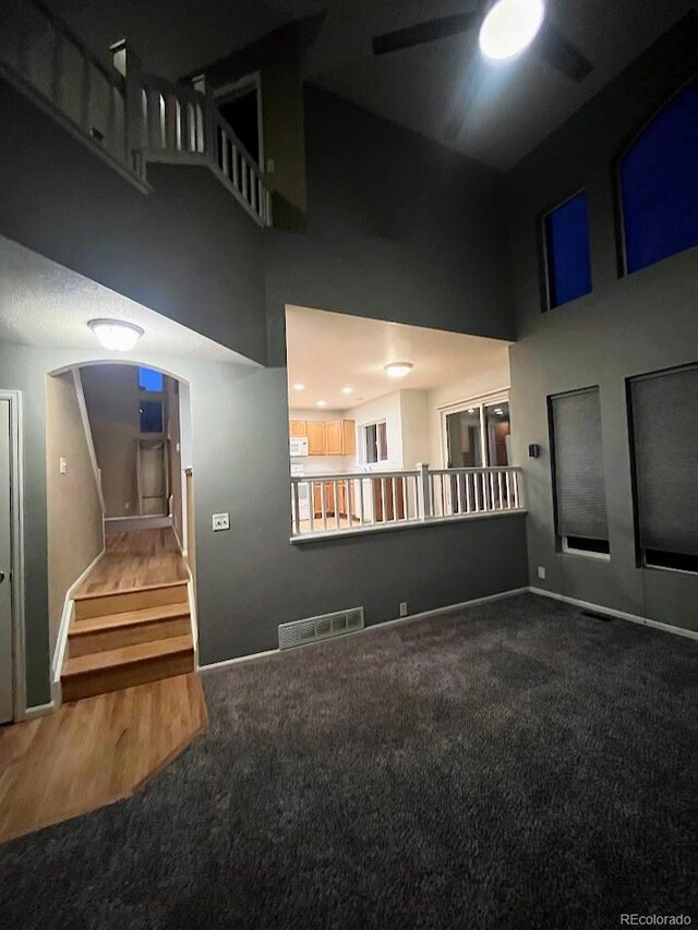 12742 Clermont St, Thornton, CO 80241 - unfurnished living room featuring a towering ceiling, carpet floors, arched walkways, ceiling fan, and stairs