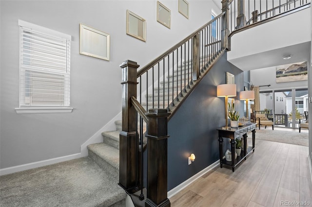 stairs featuring a towering ceiling and hardwood / wood-style flooring