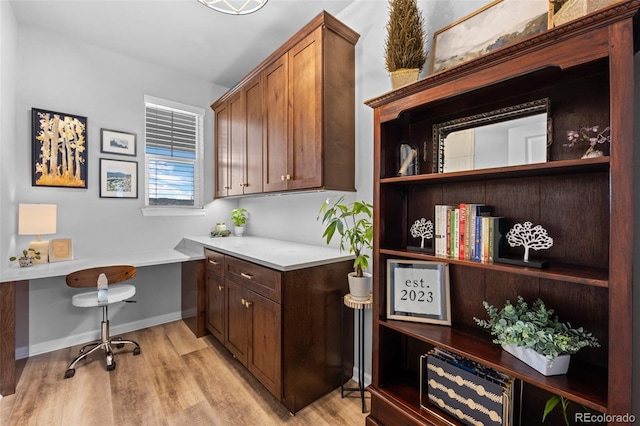 office space with built in desk and light hardwood / wood-style floors