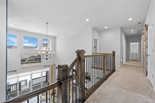 hallway featuring a barn door, carpet floors, and a chandelier